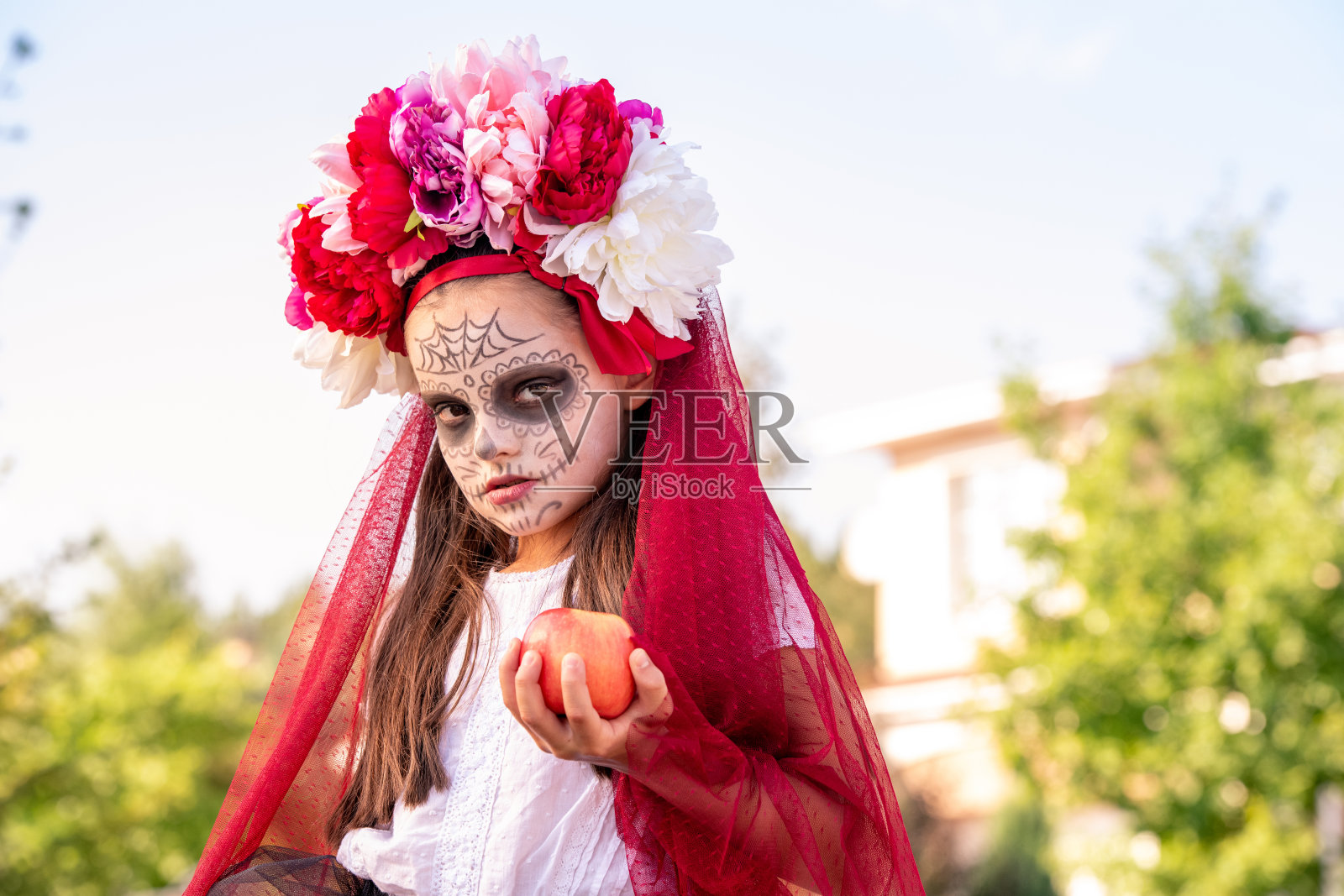 年轻阴沉的女孩与万圣节的油漆在脸上和美丽的花朵在头上照片摄影图片