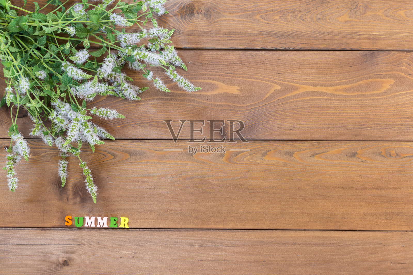 棕色的木桌上放着一束盛开的牛至。阳光明媚的夏天。五彩缤纷的信件照片摄影图片