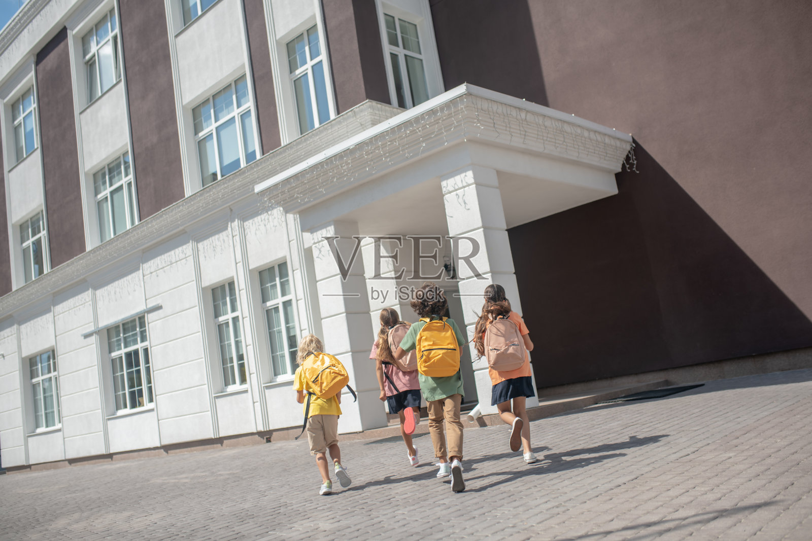 孩子们背着书包在放学后的操场上玩照片摄影图片