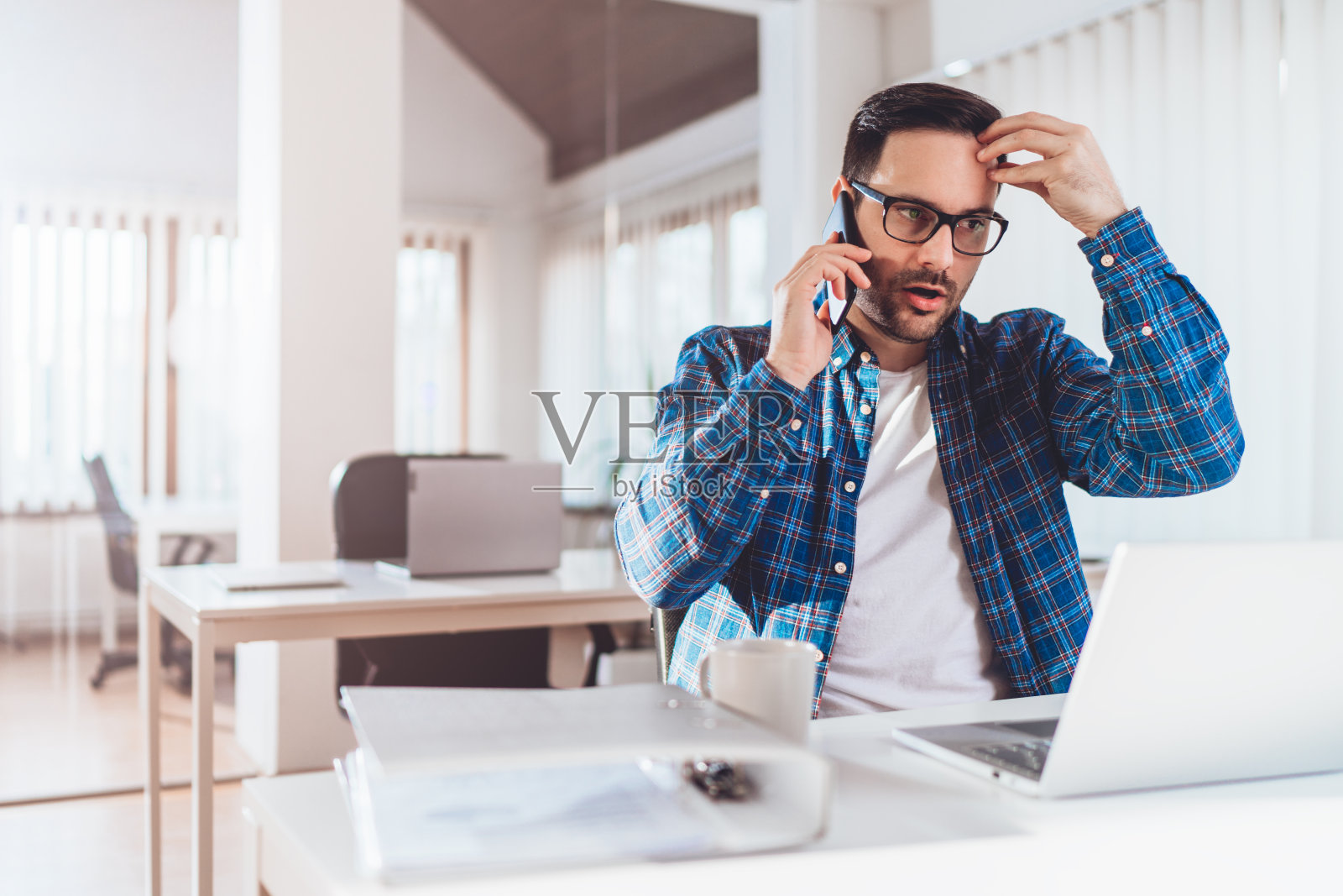 忧心忡忡的商人坐在桌边讲电话照片摄影图片