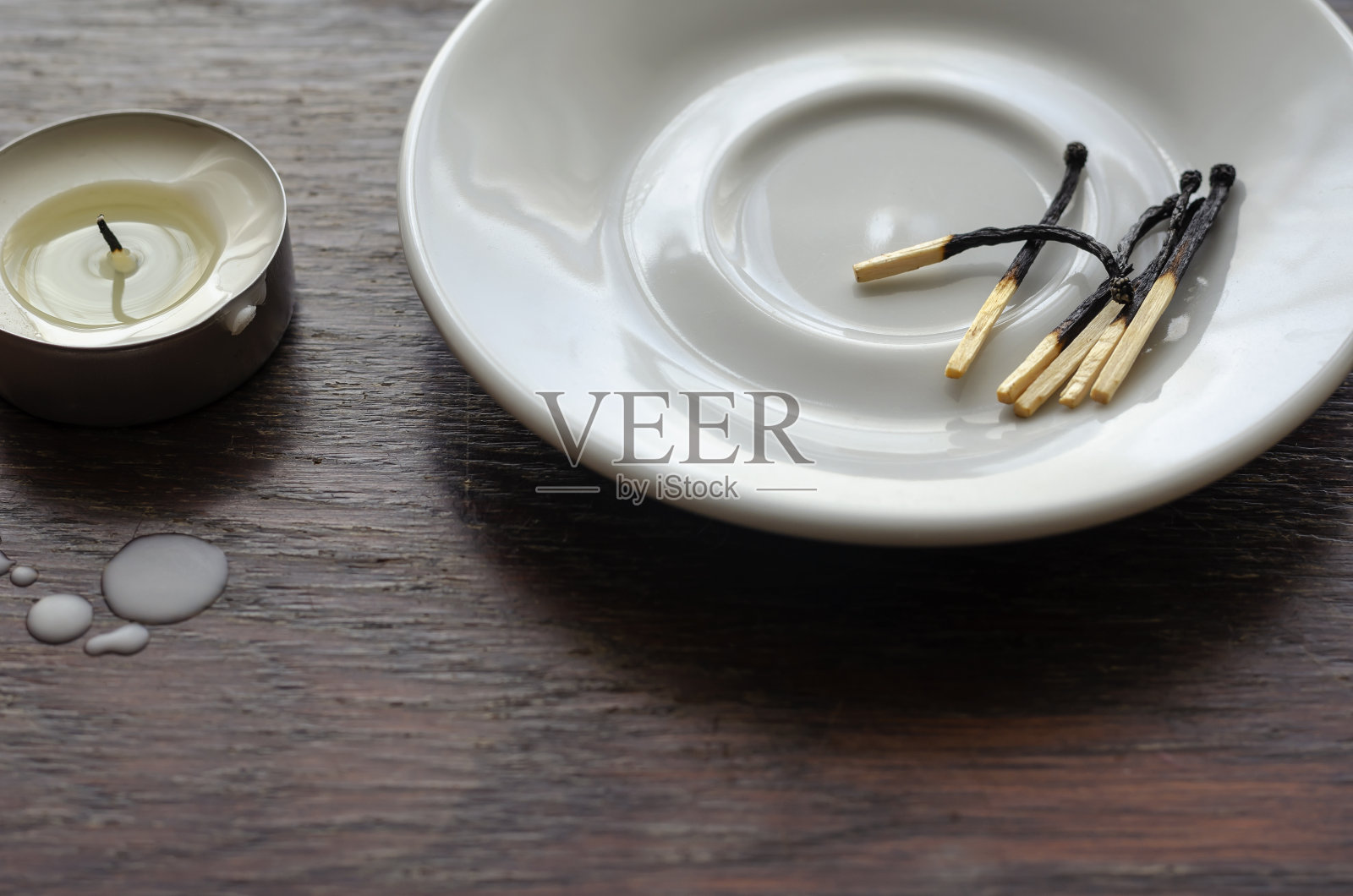 木桌上放着一根昏暗的小蜡烛。照片摄影图片