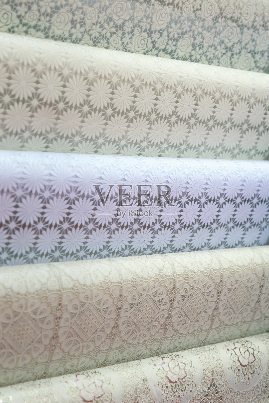 背景有许多不同的桌布，油布桌布卷在一个展示选择，挂在一个商店的陈列柜出售照片摄影图片