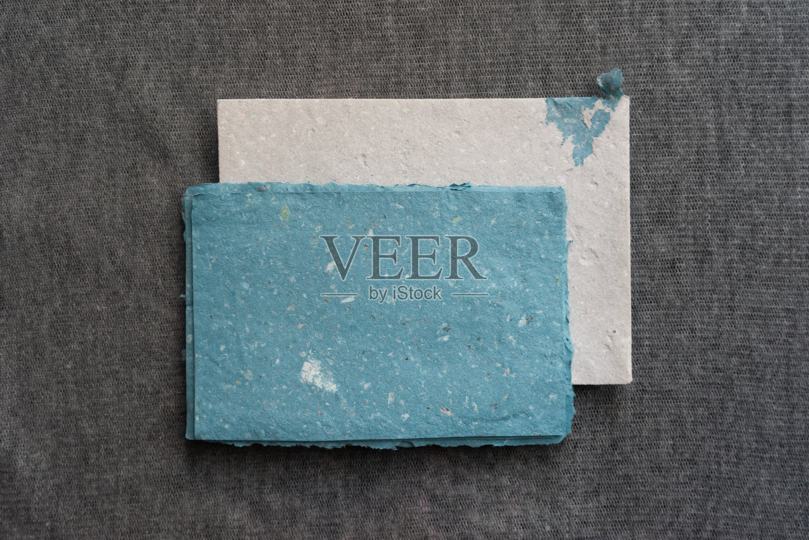 灰色的表面上放着一套手工信封和一张张纸。纸张回收和零浪费理念。照片摄影图片