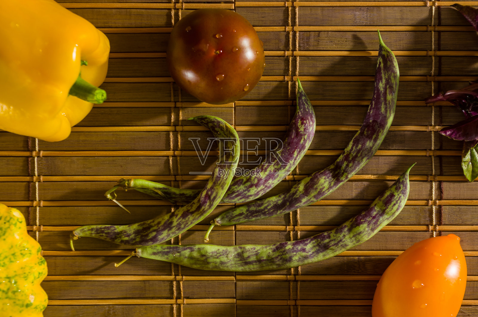 秋季静物-小斑点南瓜，芦笋豆，紫色罗勒，辣椒，黄色和巧克力西红柿在竹席上照片摄影图片