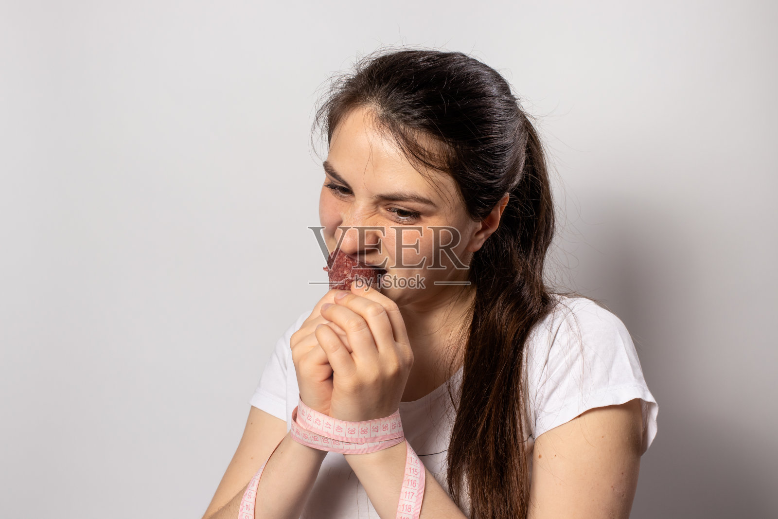 一个女人吃着熏香肠，咬得很凶。在减肥的同时中断饮食。照片摄影图片