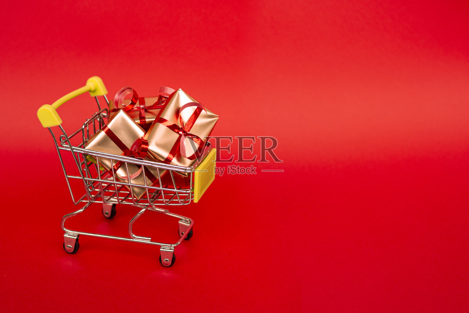 圣诞节销售。购物篮与金色礼品盒与红丝带在红色的背景横幅与复制空间。圣诞节的网上购物。冬季假期销售，季节性销售，黑色星期五，圣诞节，折扣和网上购物。照片摄影图片