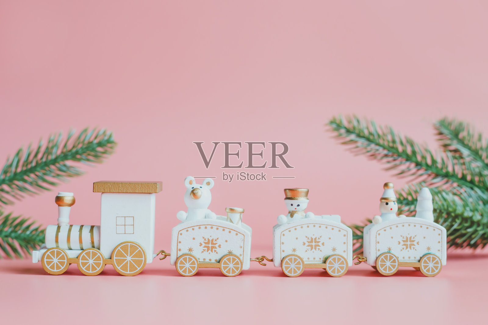 圣诞或新年节日贺卡。粉红色背景上的玩具火车。照片摄影图片