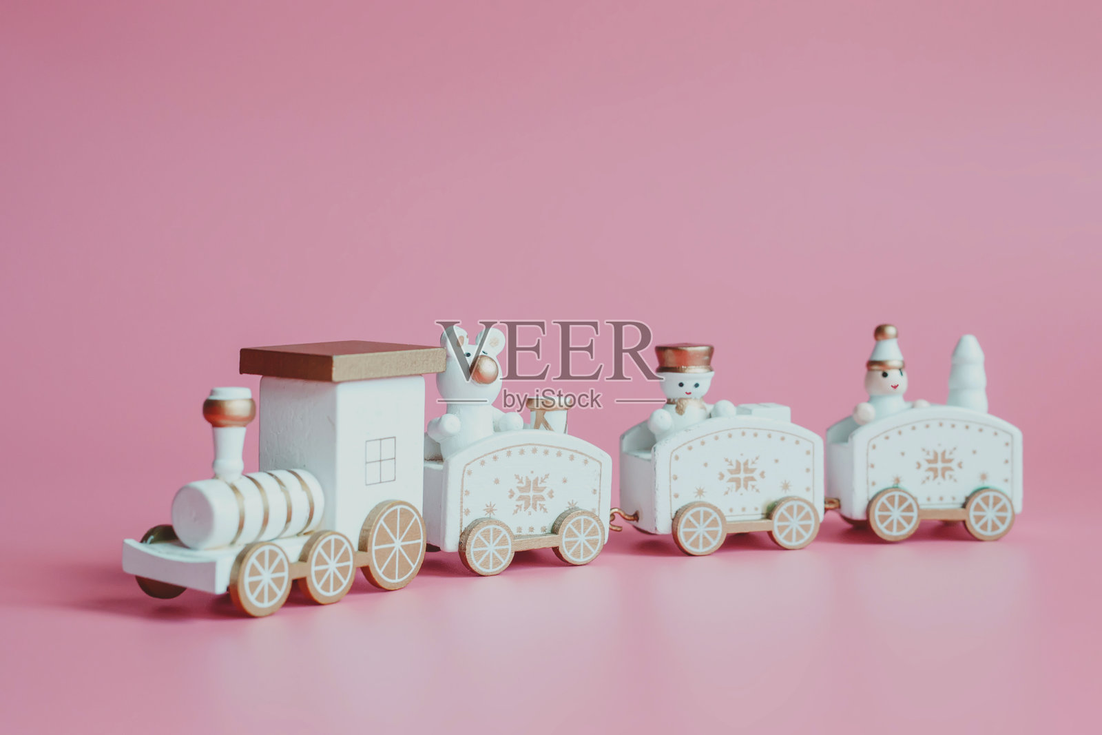圣诞或新年节日贺卡。粉红色背景上的玩具火车。照片摄影图片