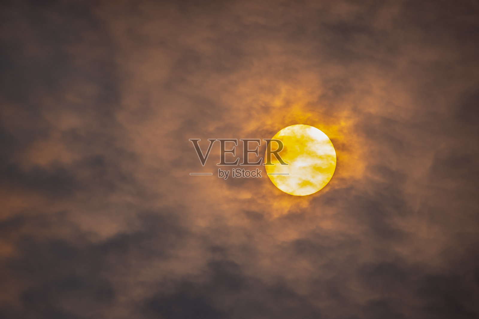 通过烟和灰烬的云升起的太阳的远摄视图照片摄影图片