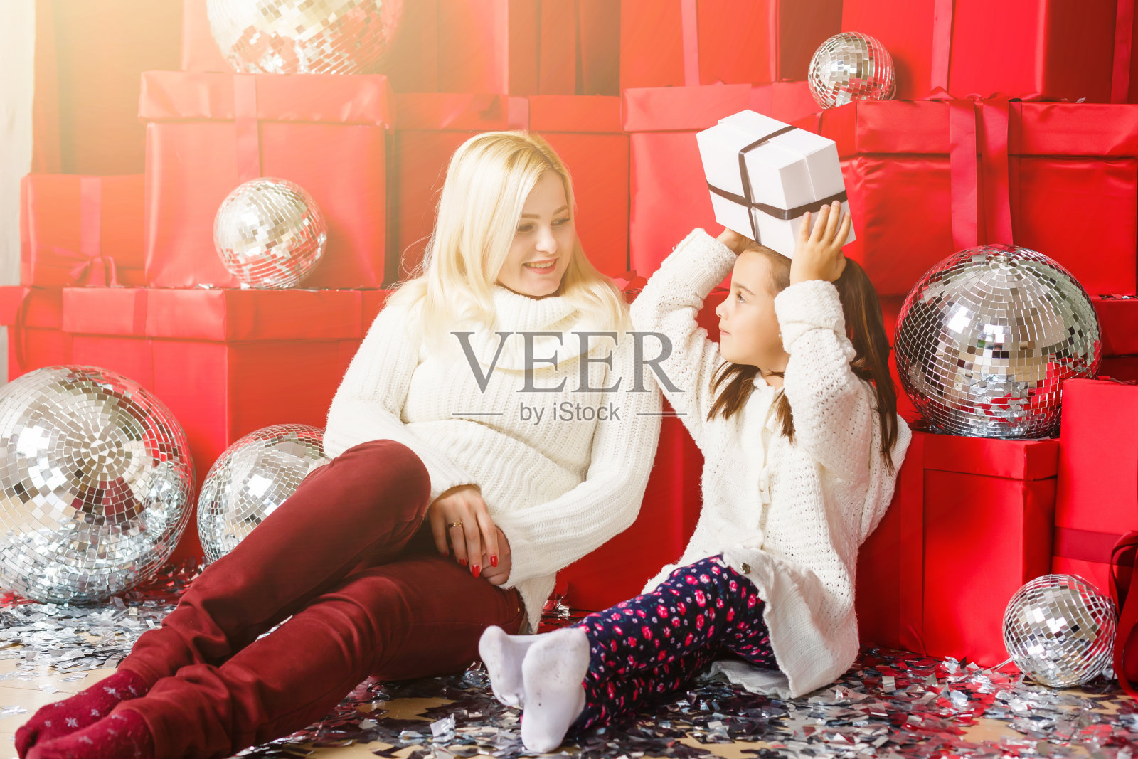 圣诞快乐，节日快乐!快乐的妈妈和她可爱的女儿交换礼物。父母和孩子有乐趣附近的圣诞树室内。爱的家庭和礼物在房间里。照片摄影图片