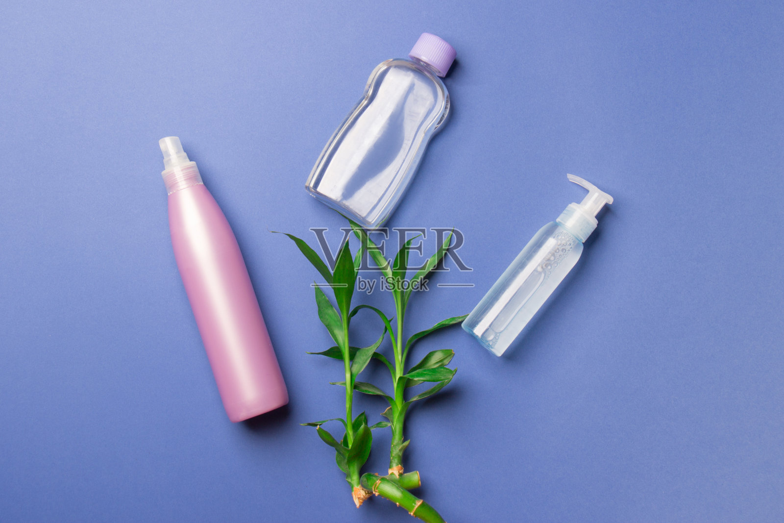 三个化妆瓶竹枝蓝纸背景。俯视图照片摄影图片