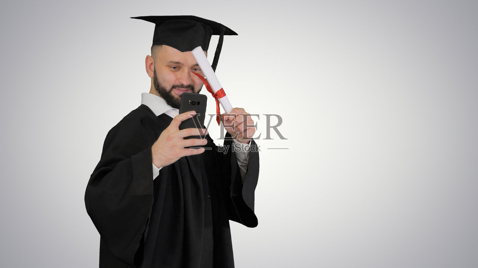 身着毕业长袍的男子与d边走边自拍照片摄影图片