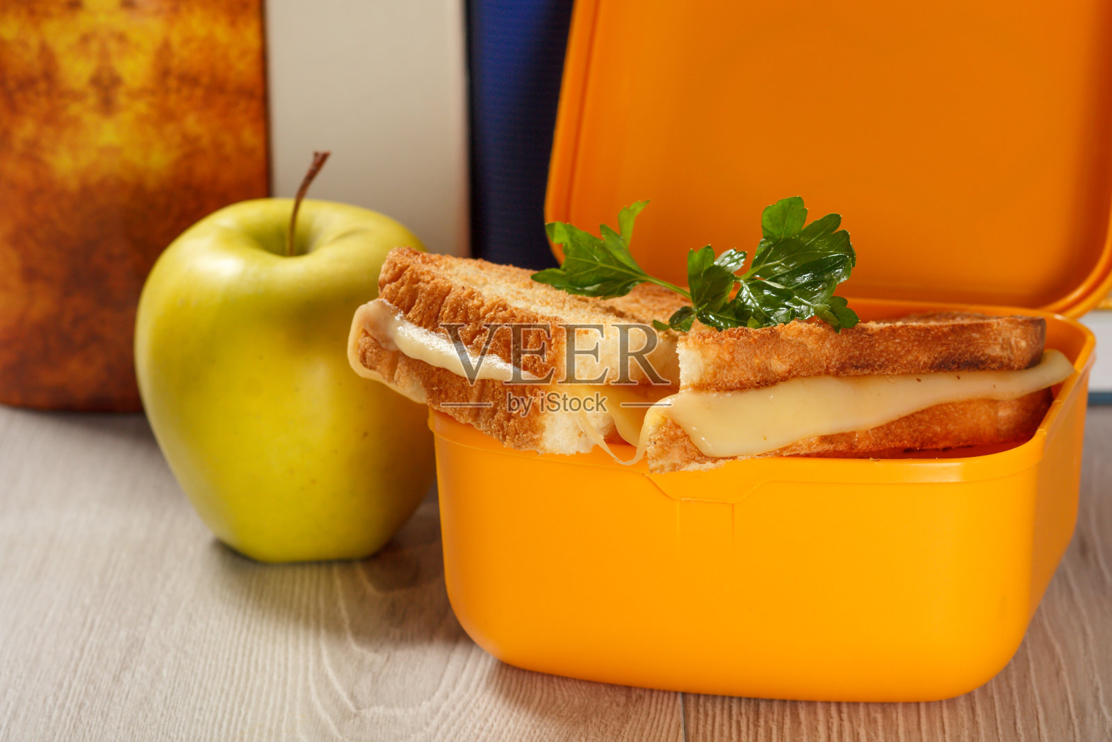 黄色的午餐盒，里面有烤面包片，奶酪，欧芹，青苹果。照片摄影图片