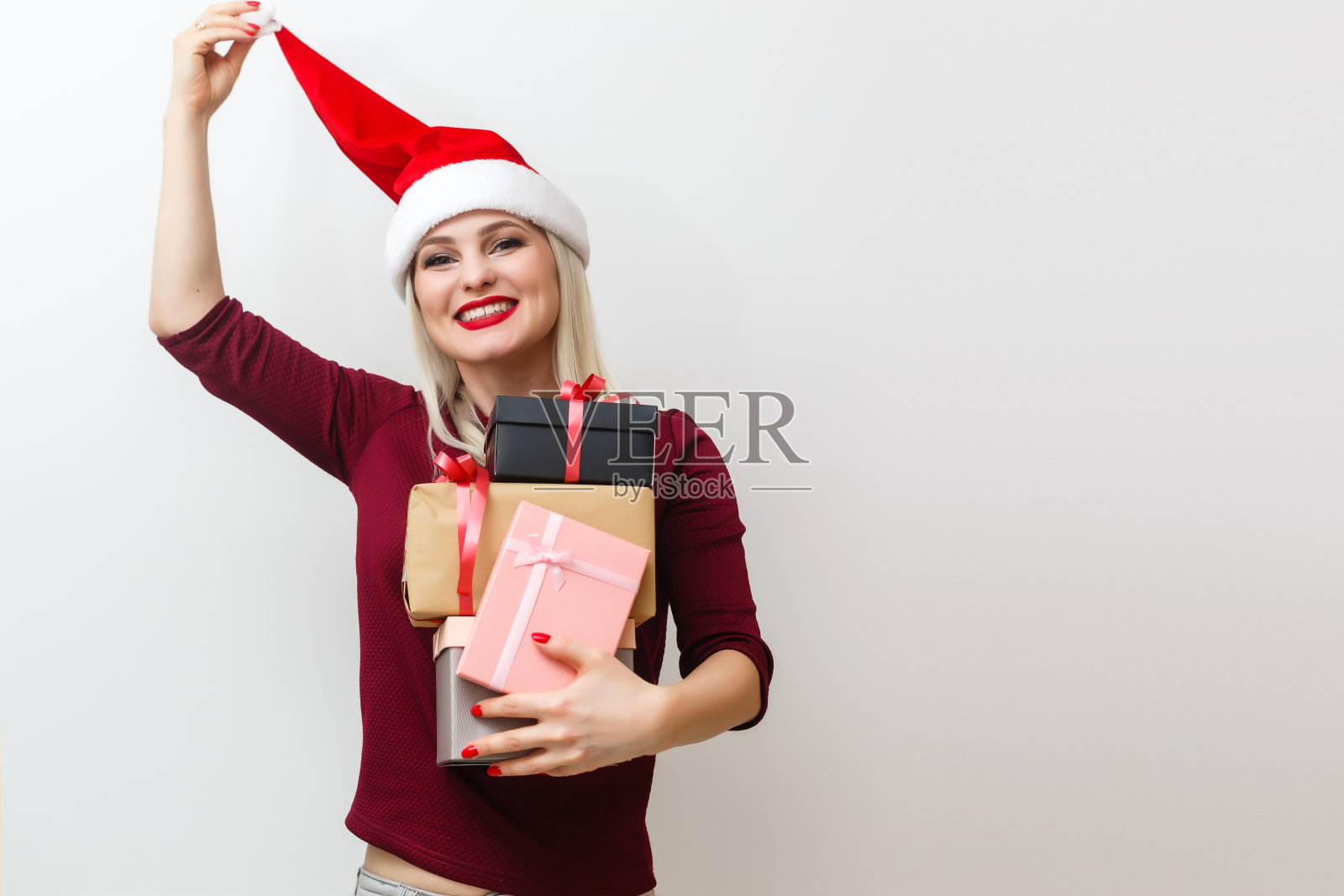 微笑的女孩躲在圣诞礼物后面。灰色的使用。照片摄影图片