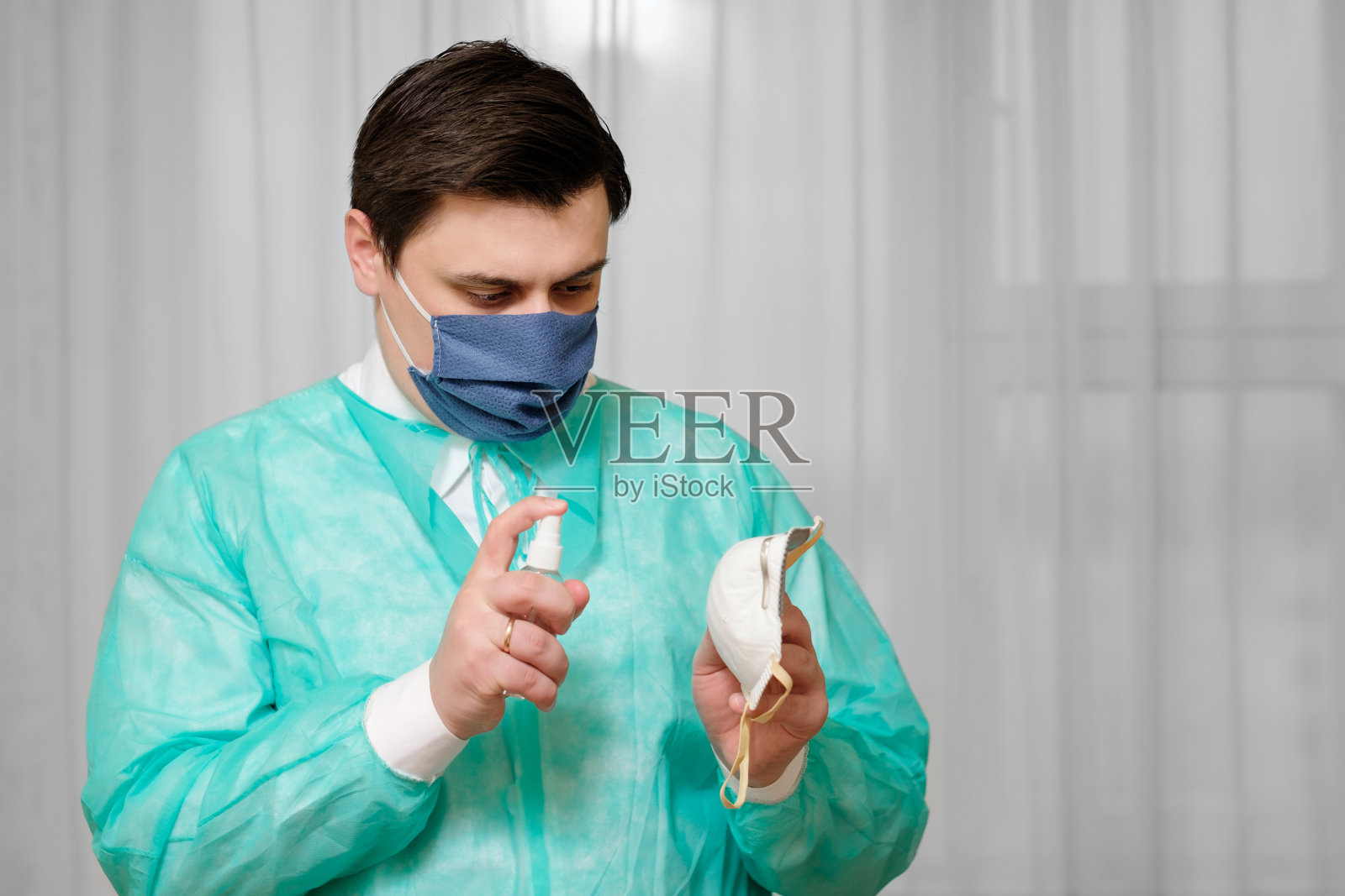 医生用消毒剂喷雾对使用过的医用防护口罩进行消毒照片摄影图片