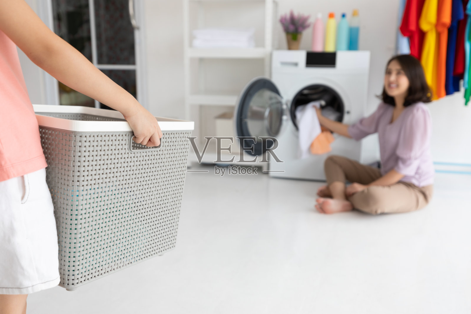 特写孩子拿着洗衣篮，和妈妈在一起的小帮手，微笑着在家洗衣服照片摄影图片