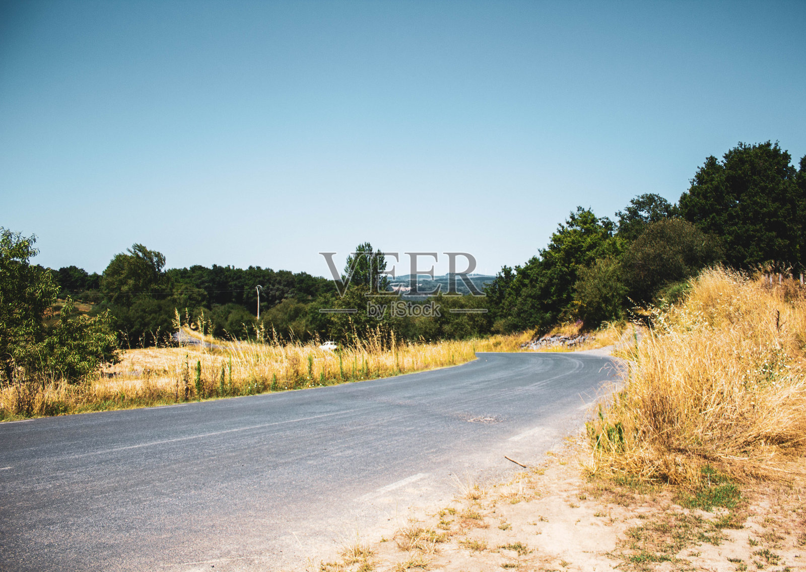 道路穿过田野，群山映衬着蓝天照片摄影图片
