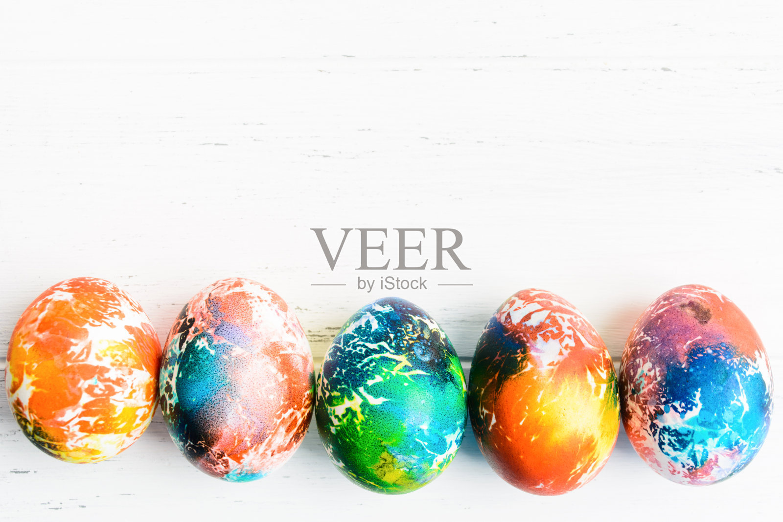 复活节彩蛋放在质朴的白色木桌上。节日的背景。彩色的鸡蛋排成一行。俯视图照片摄影图片