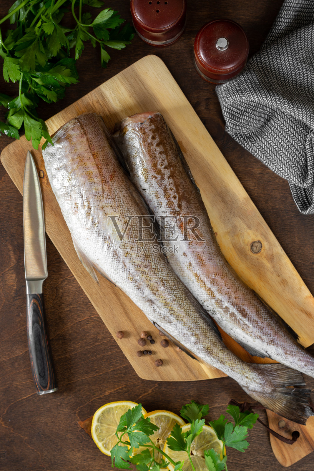 鳕鱼鱼。棕色餐桌上的菜板上的波洛克。烹饪鱼的准备工作。俯视图照片摄影图片