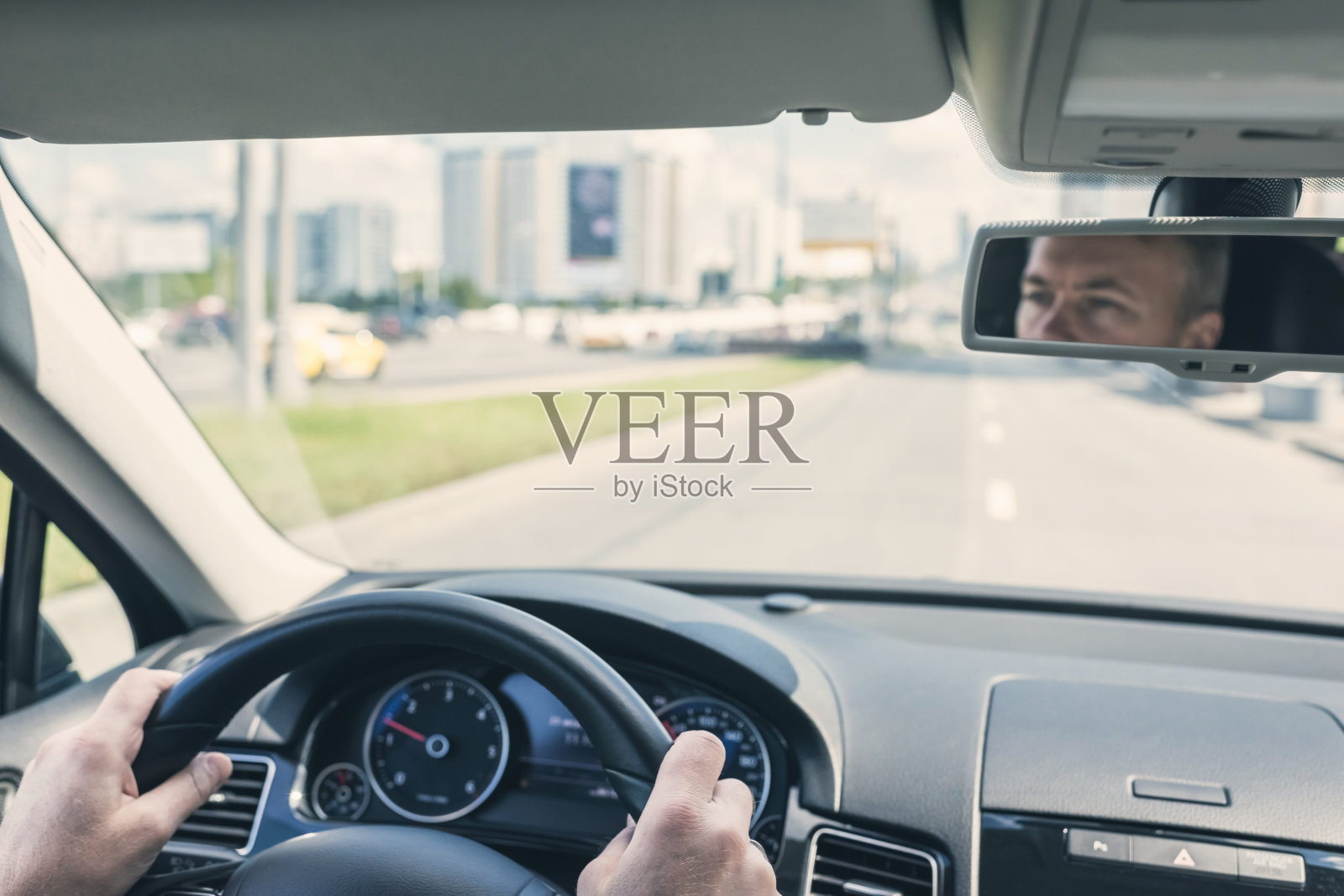 在高速公路上驾驶汽车时，有选择地集中人手在方向盘上。从上面的观点照片摄影图片