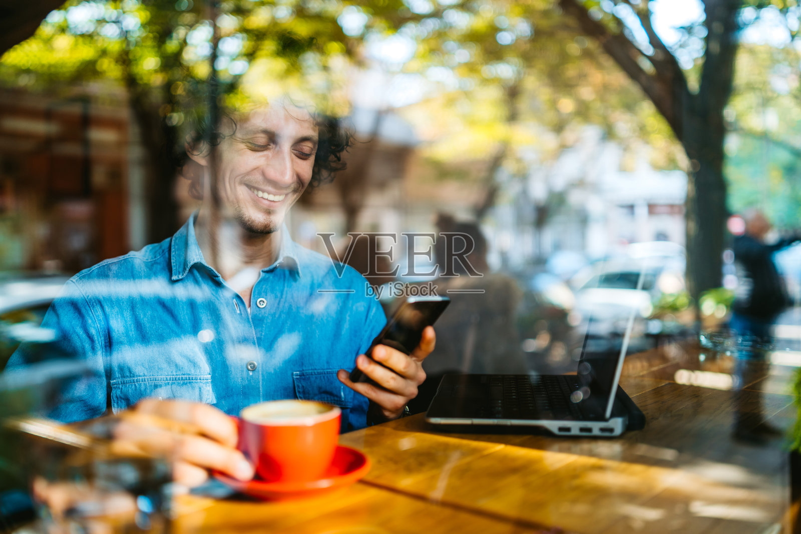 在咖啡店用笔记本电脑和智能手机的男人照片摄影图片