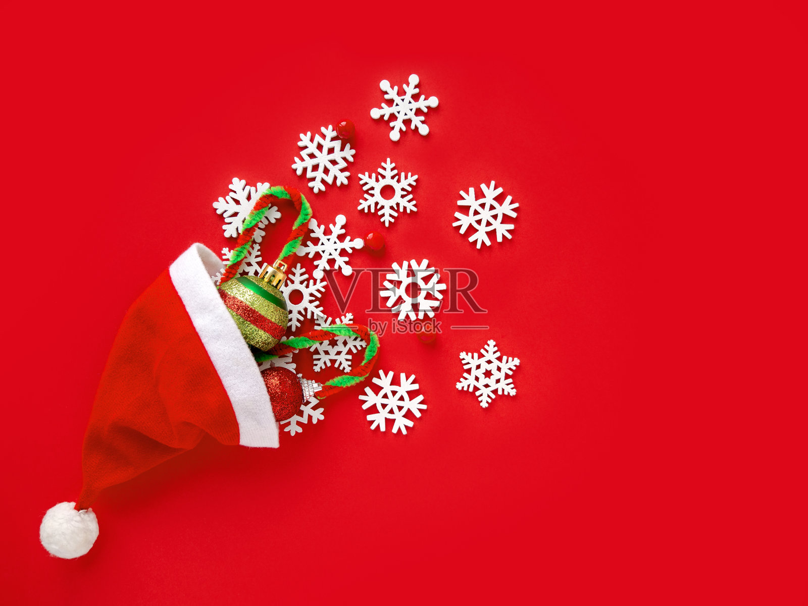 新年。圣诞老人的帽子，白色的雪花和圣诞饰品在明亮的红色背景。俯视图，复制空间照片摄影图片