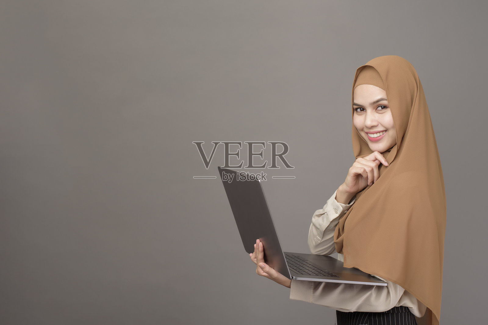 戴头巾的美丽女人肖像，手持笔记本电脑照片摄影图片