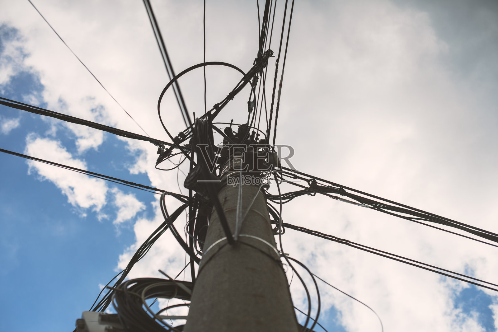 在多云的天空下，有许多电线电缆的混凝土电力线路照片摄影图片