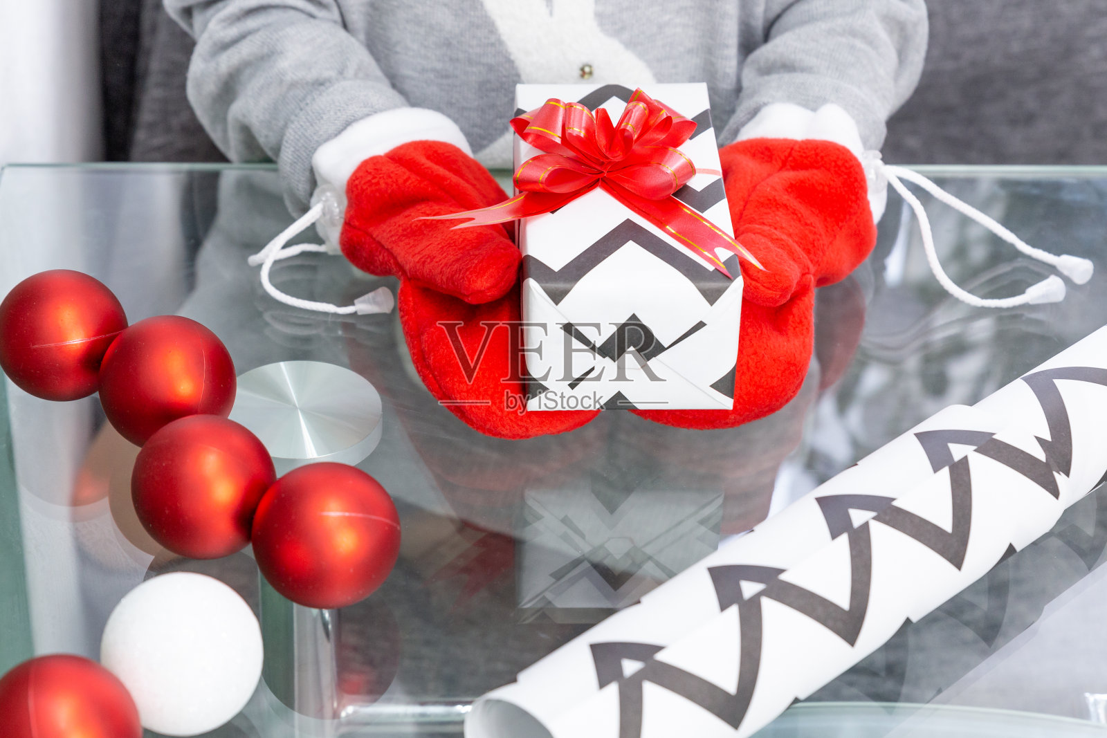 一个穿着灰色毛衣和一只兔子的女孩拿着一份礼物，手里拿着红色的手套。新年，圣诞节，寒假照片摄影图片