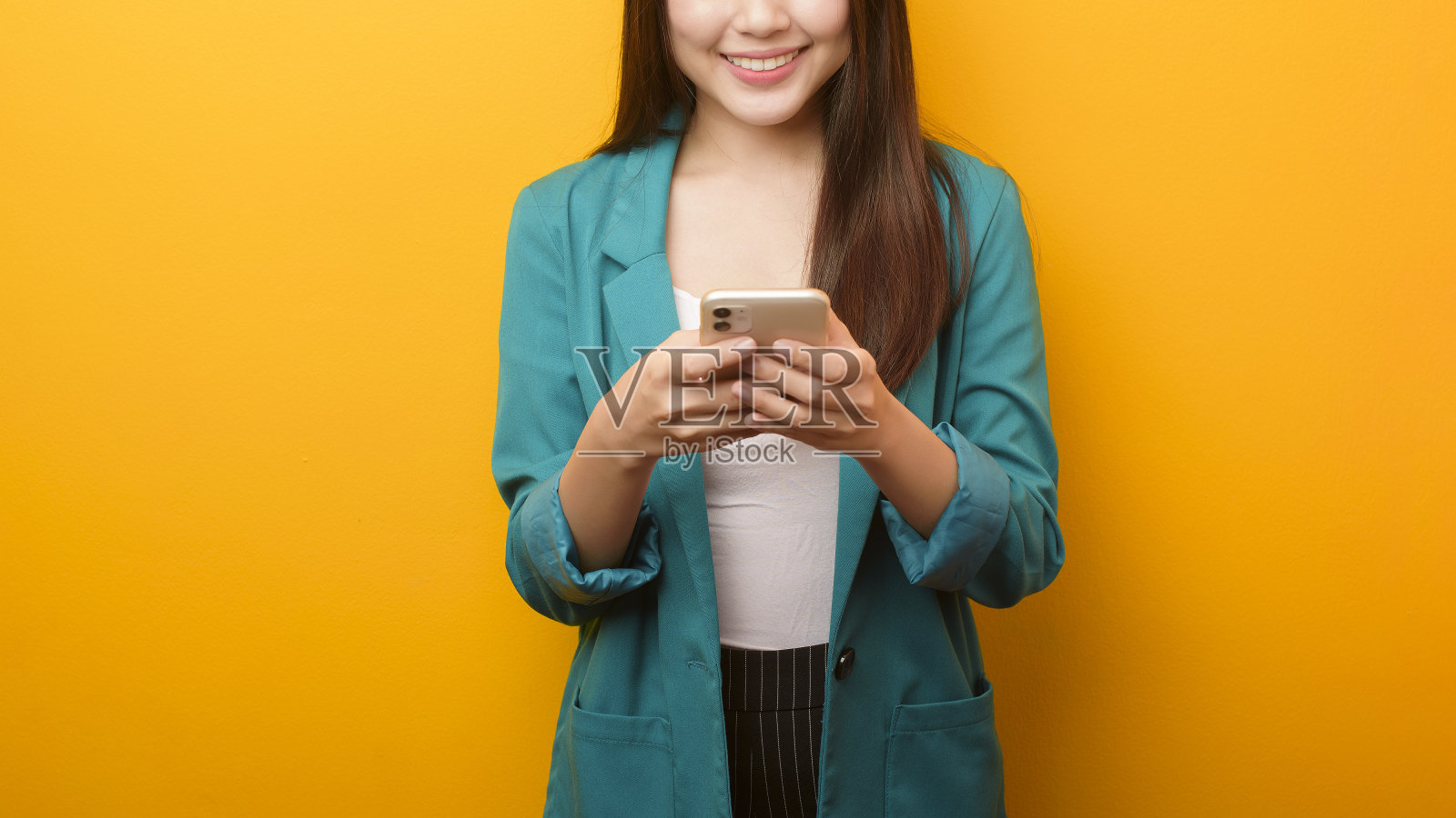 时尚肖像美丽的女人在绿色套装使用手机在黄色的背景照片摄影图片