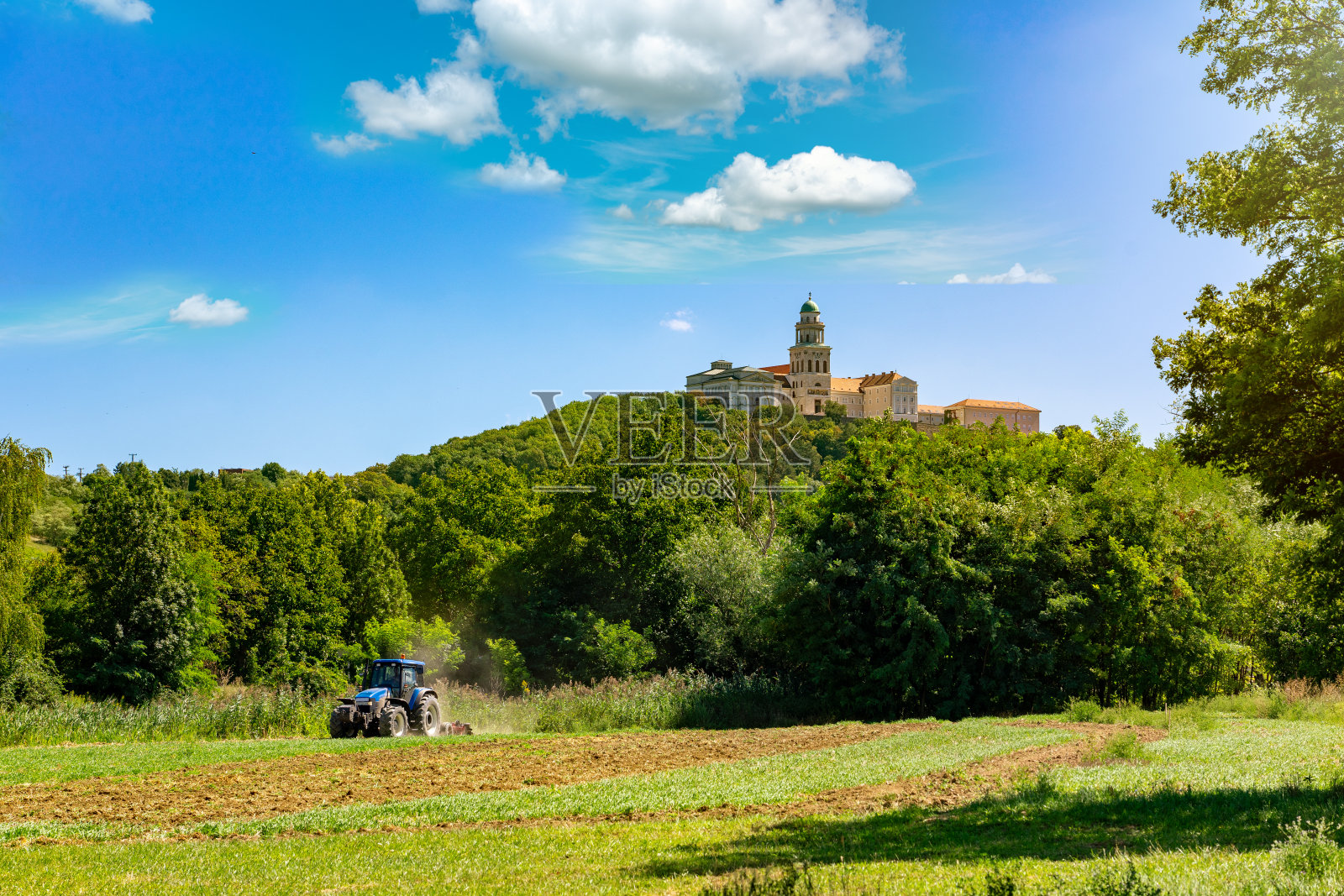 帕农哈尔马修道院的山上有农地和拖拉机在夏天照片摄影图片