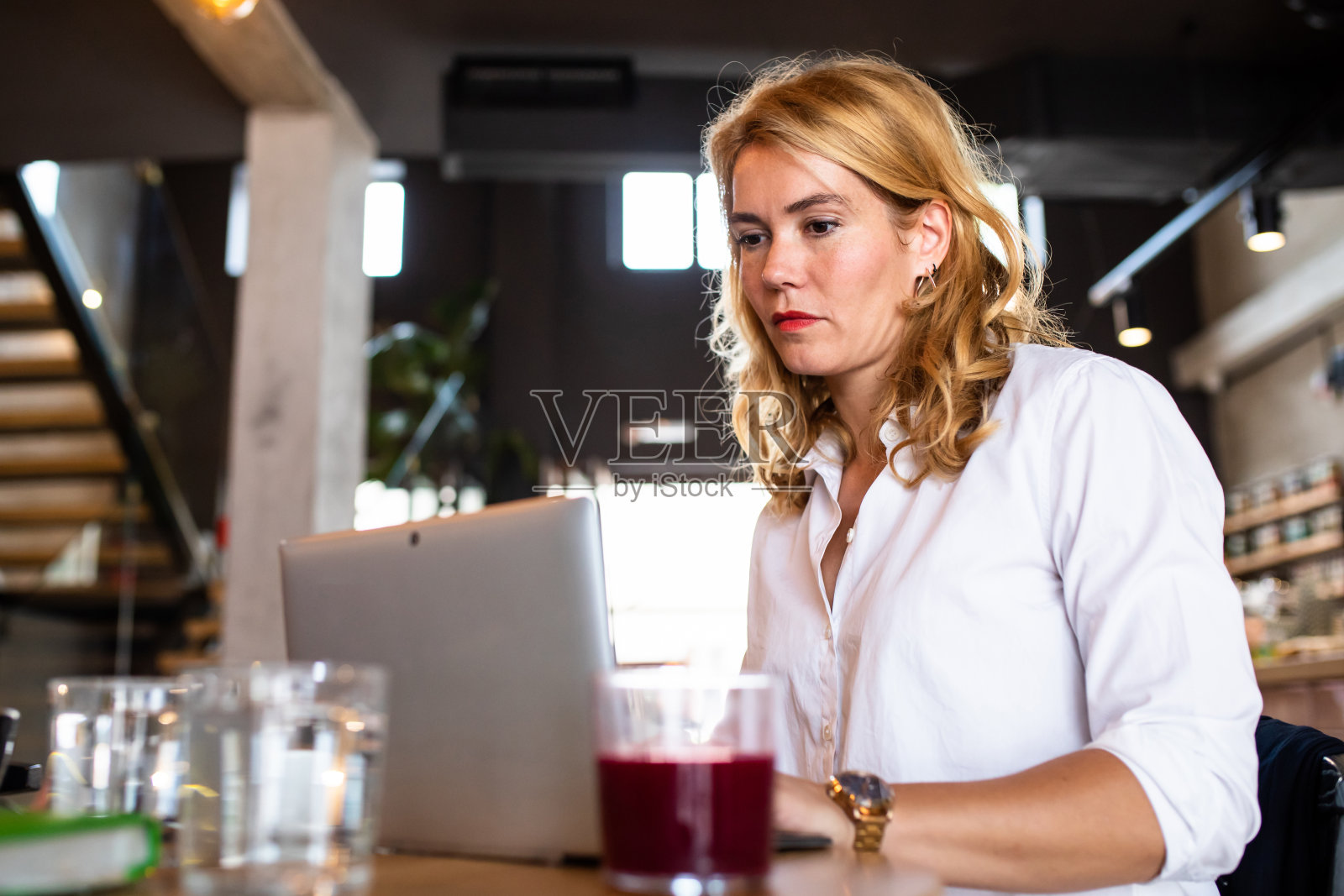 一个漂亮的金发女商人在笔记本电脑上打字照片摄影图片