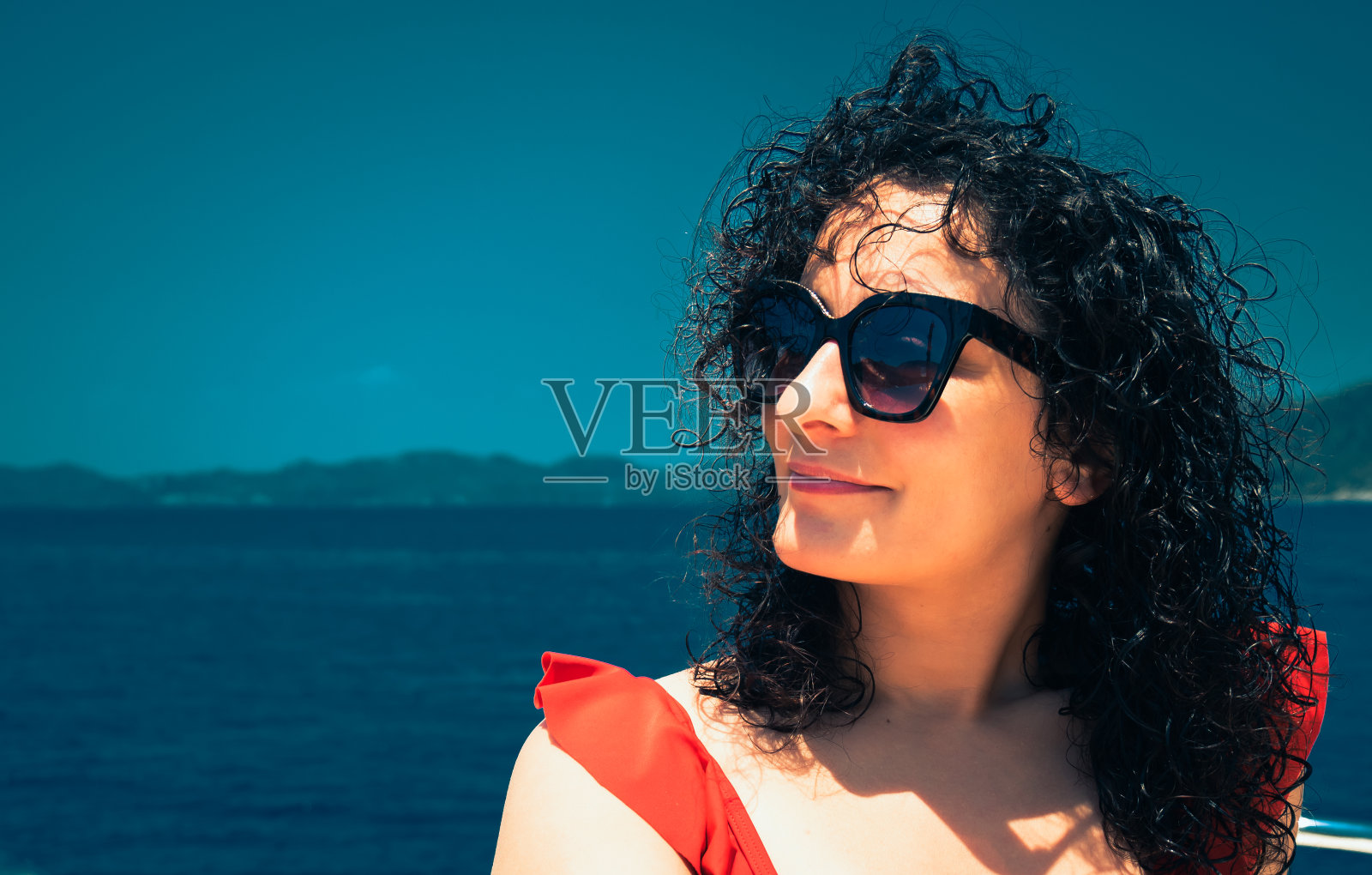 肖像美丽的卷发女人在户外越过蓝色的海滩海水，快乐的笑脸，夏天的概念照片摄影图片