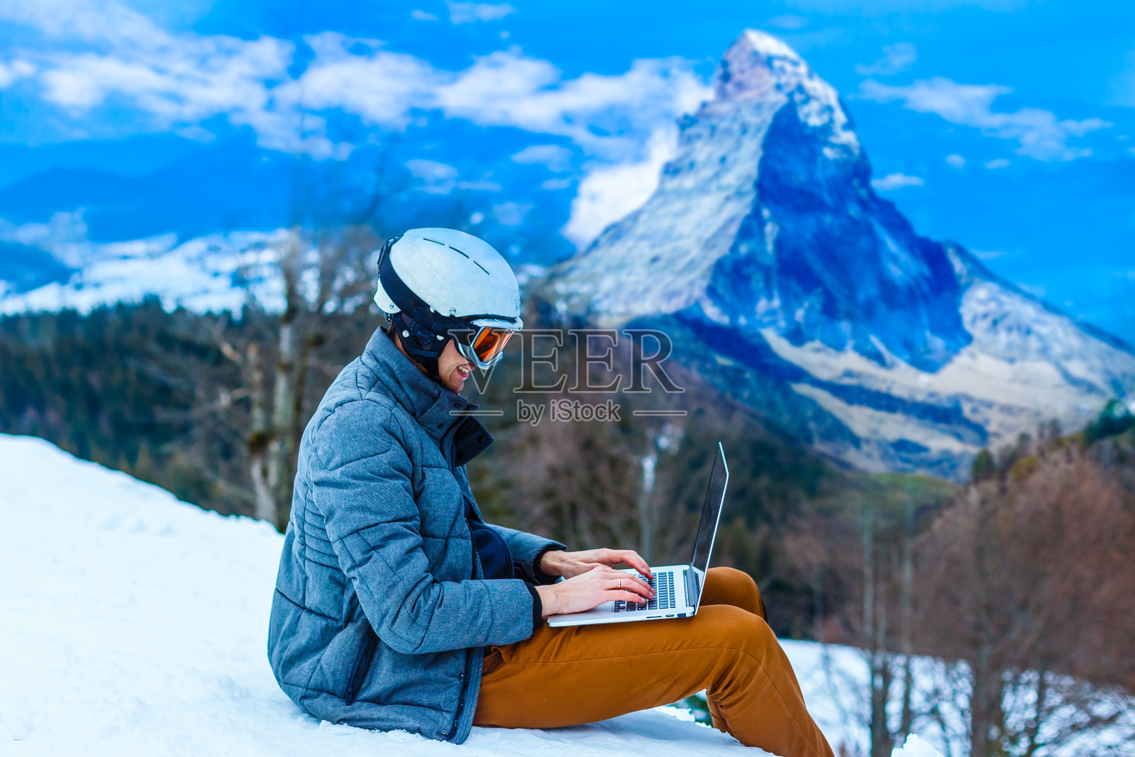 一个年轻人拿着一个小玩意坐在悬崖边上，特写照片摄影图片
