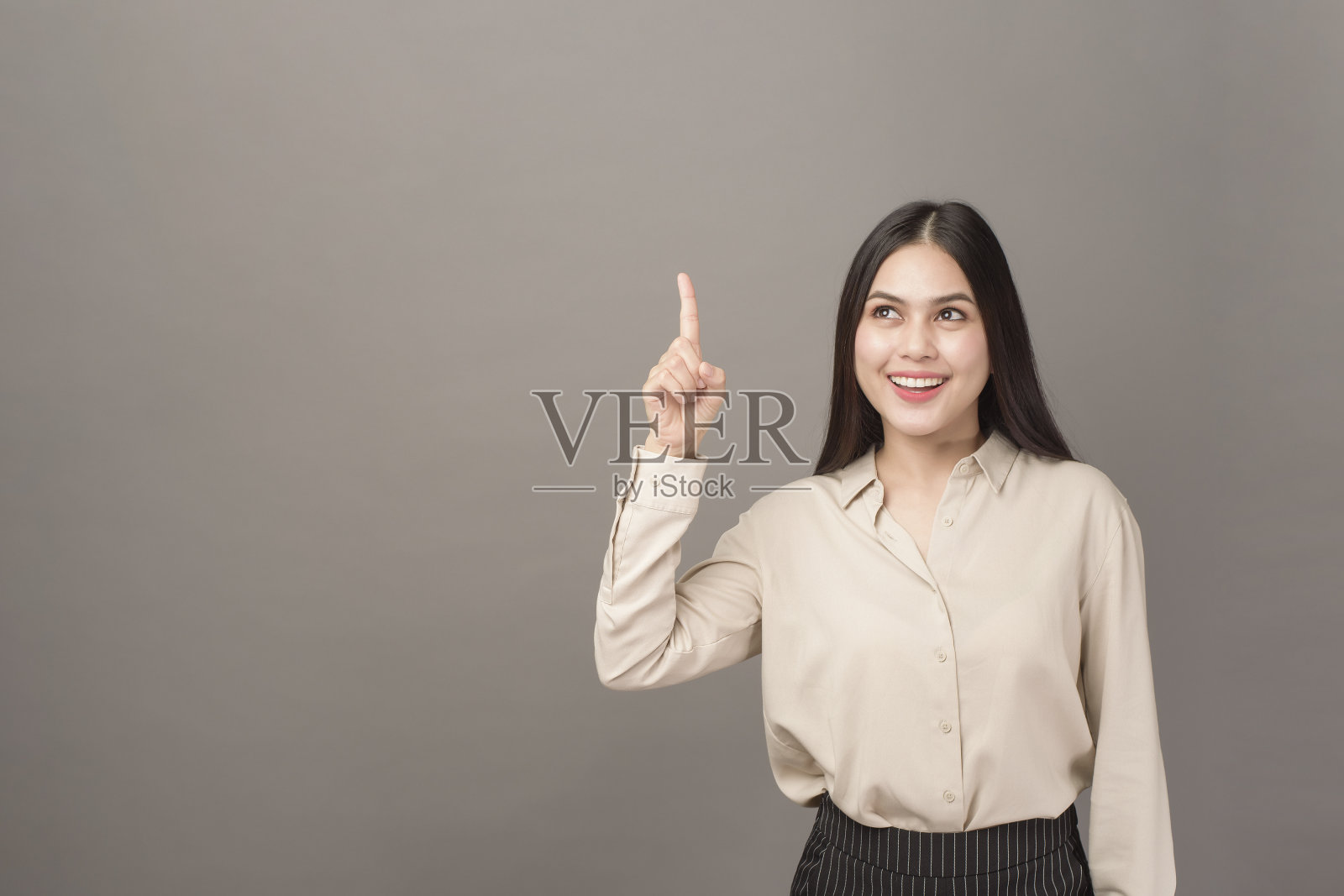 美丽的女商人的肖像显示在灰色的背景上的东西照片摄影图片