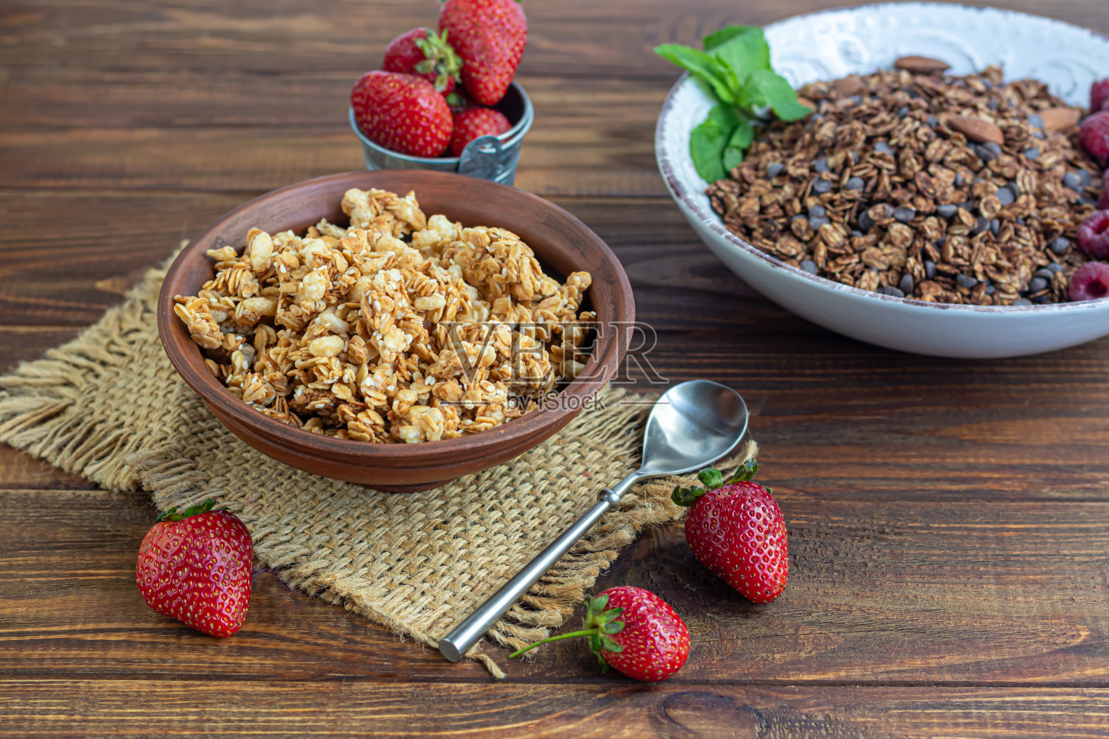 用粘土盘子装上草莓片自制格兰诺拉麦片。在木制的背景上。素食菜。乡村风格。健康的早餐。照片摄影图片