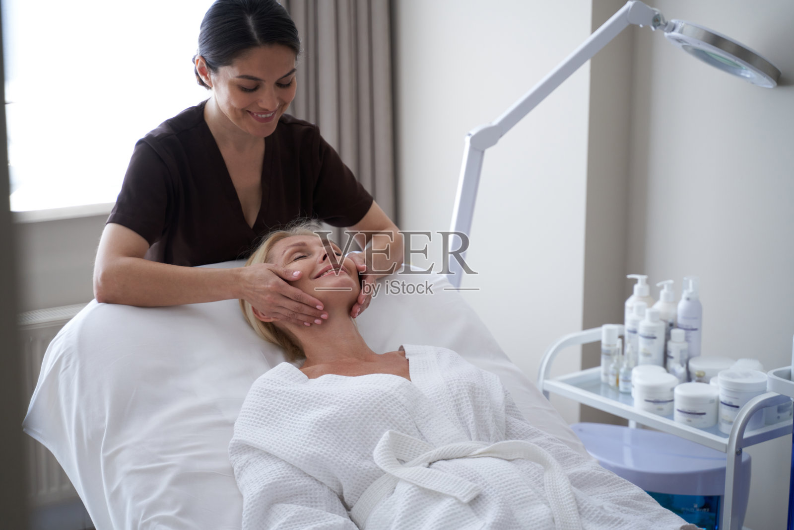 微笑的成年女性闭着眼睛坐在按摩沙发上照片摄影图片