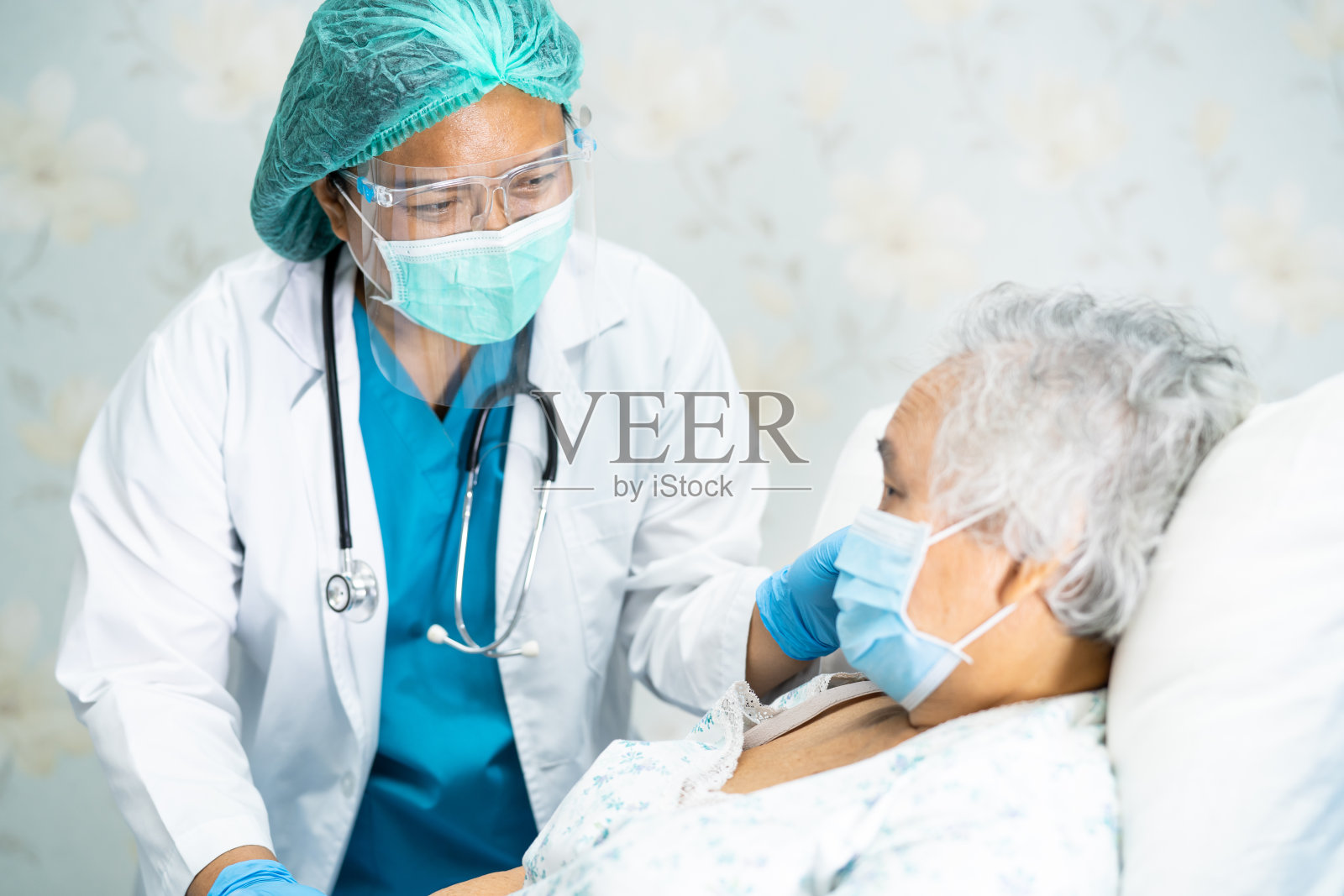 亚洲医生戴口罩和防护服新常态检查患者保护安全感染新冠肺炎疫情在隔离护理医院病房。照片摄影图片