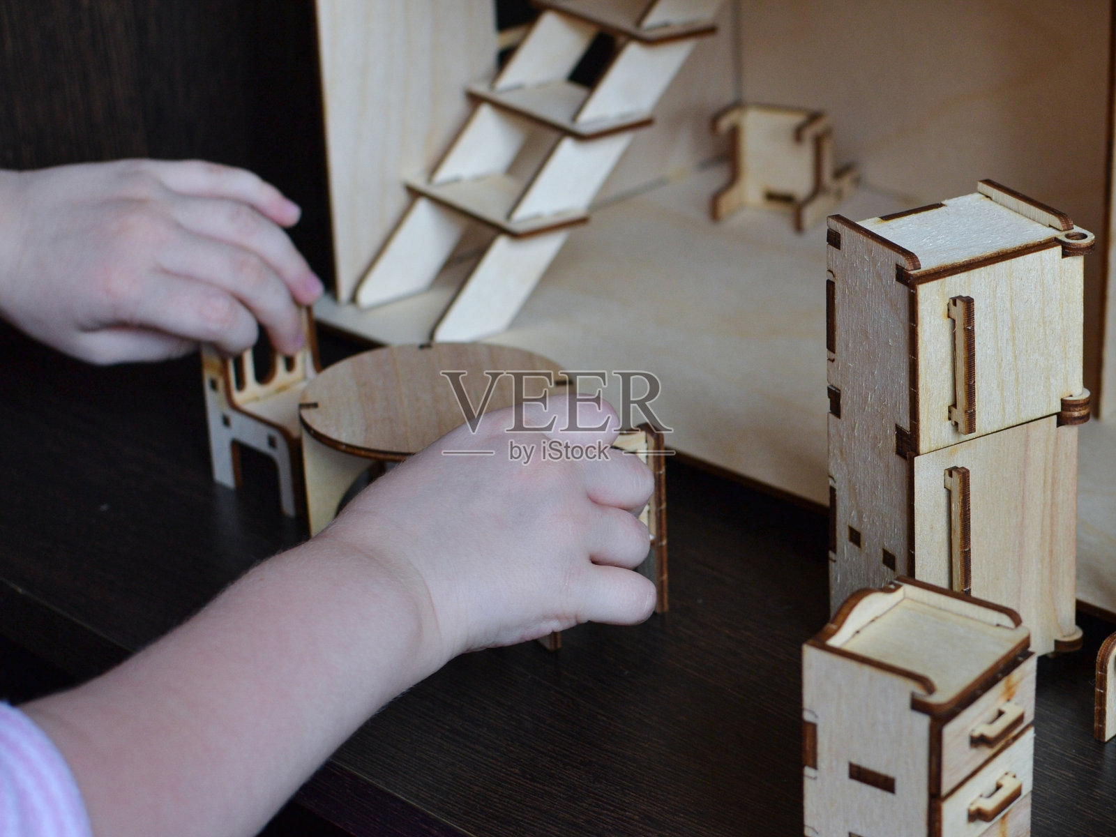 孩子们的手正在摆放娃娃的木制家具照片摄影图片