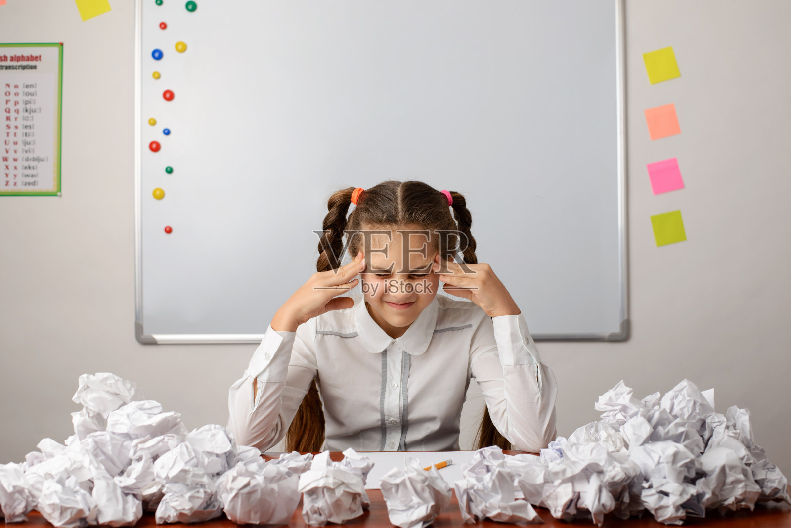 年轻的学习者坐在教室里思考作文。她试着开始工作，但失败了很多次照片摄影图片