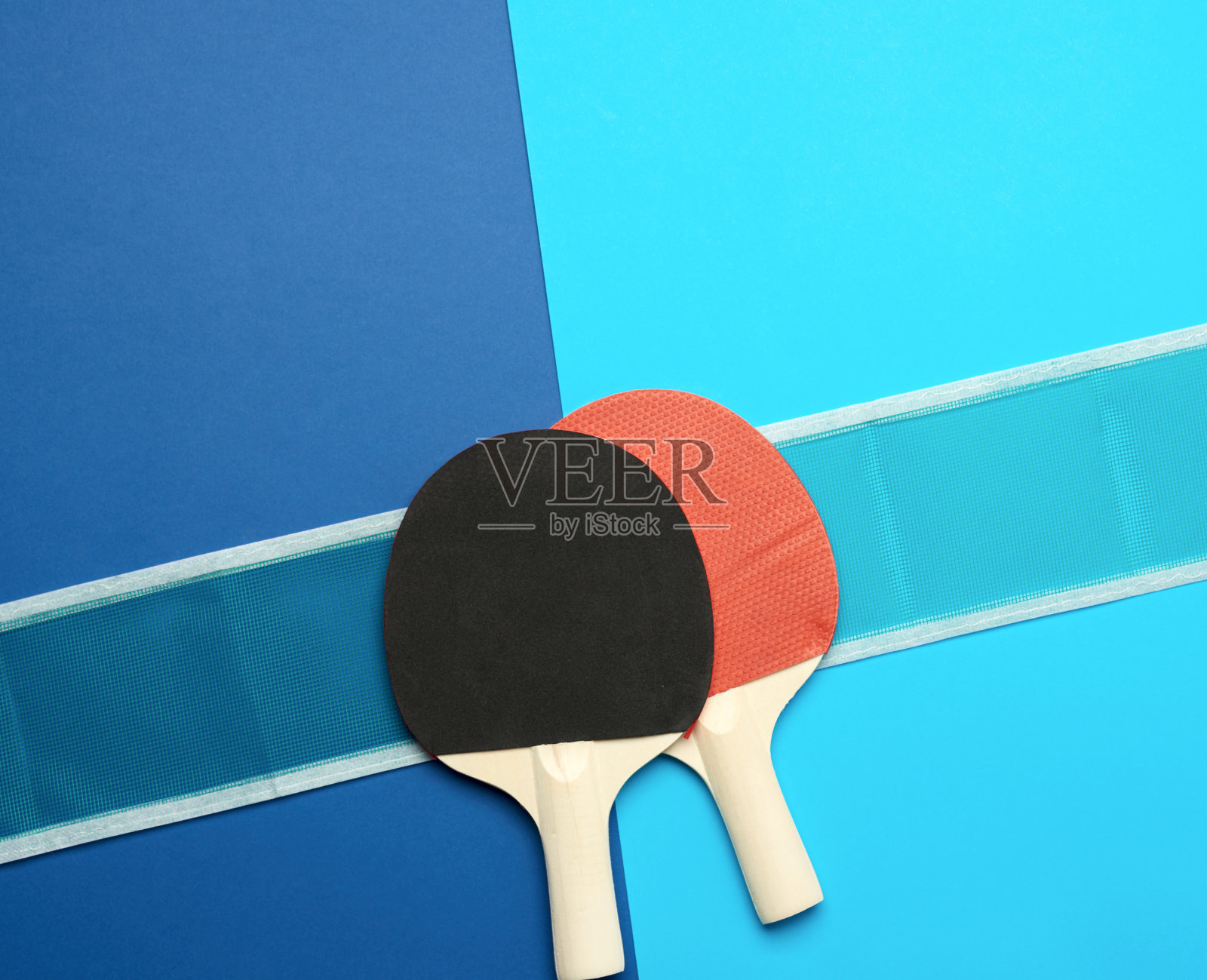 木制的乒乓球拍和蓝色背景的网照片摄影图片