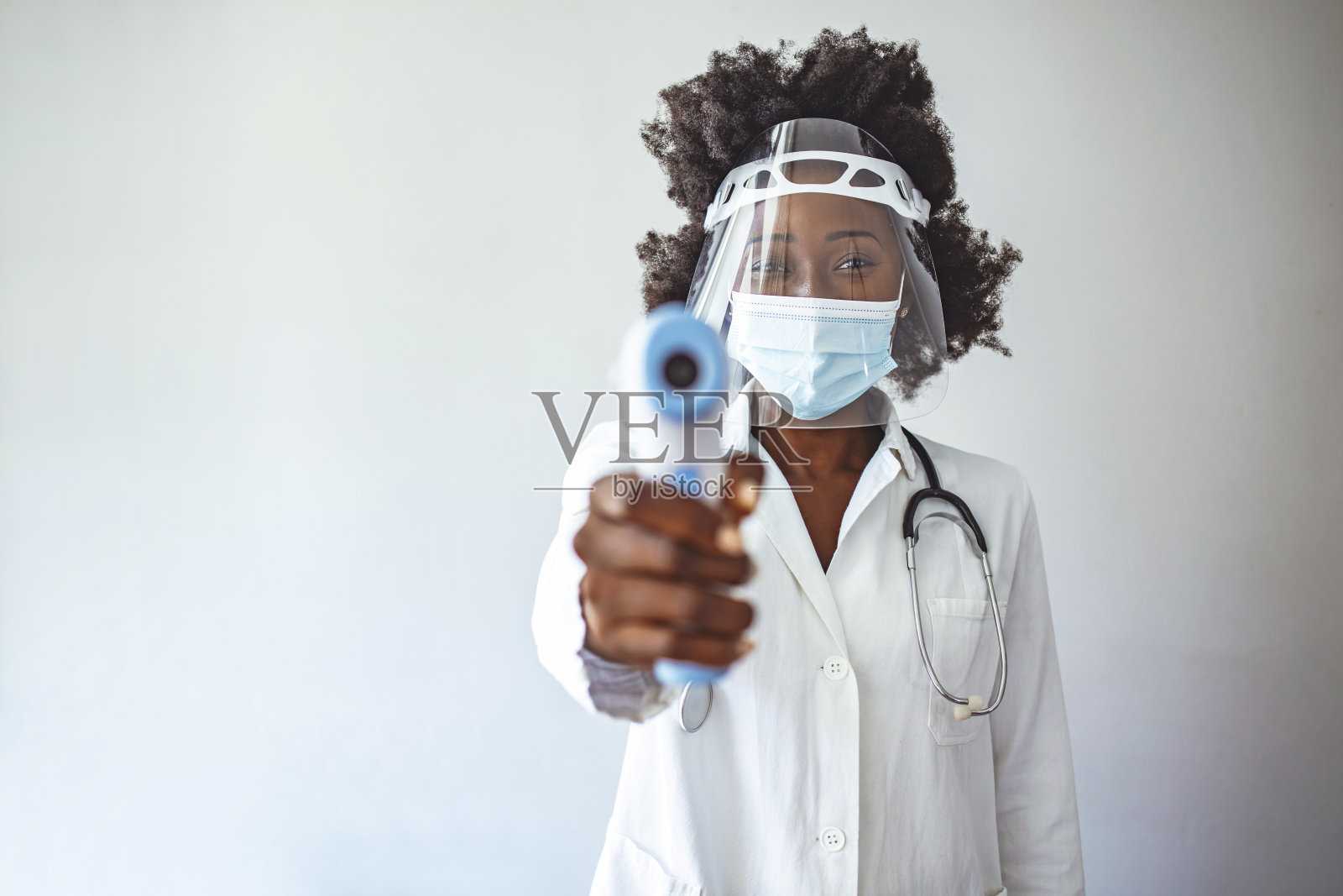 女医生用红外额头体温计枪检测体温，检测病毒covid-19症状照片摄影图片