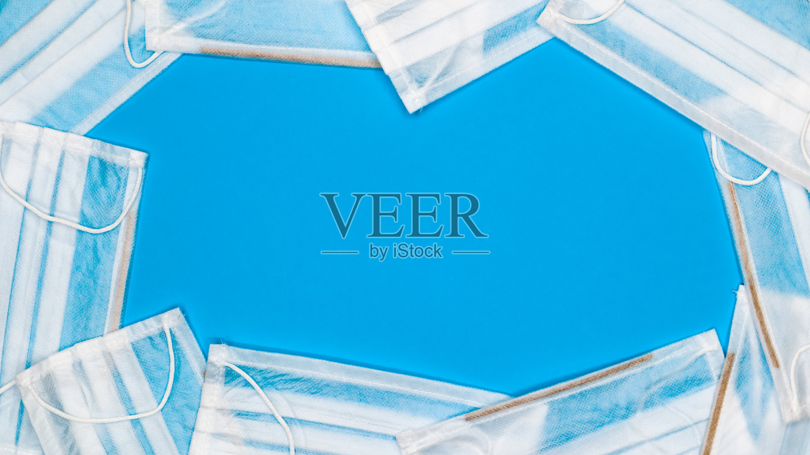 许多带有耳环的抗病毒防护医用口罩都以蓝色背景为背景。口罩的背景。呼吸综合征、冠状病毒病。本空间照片摄影图片