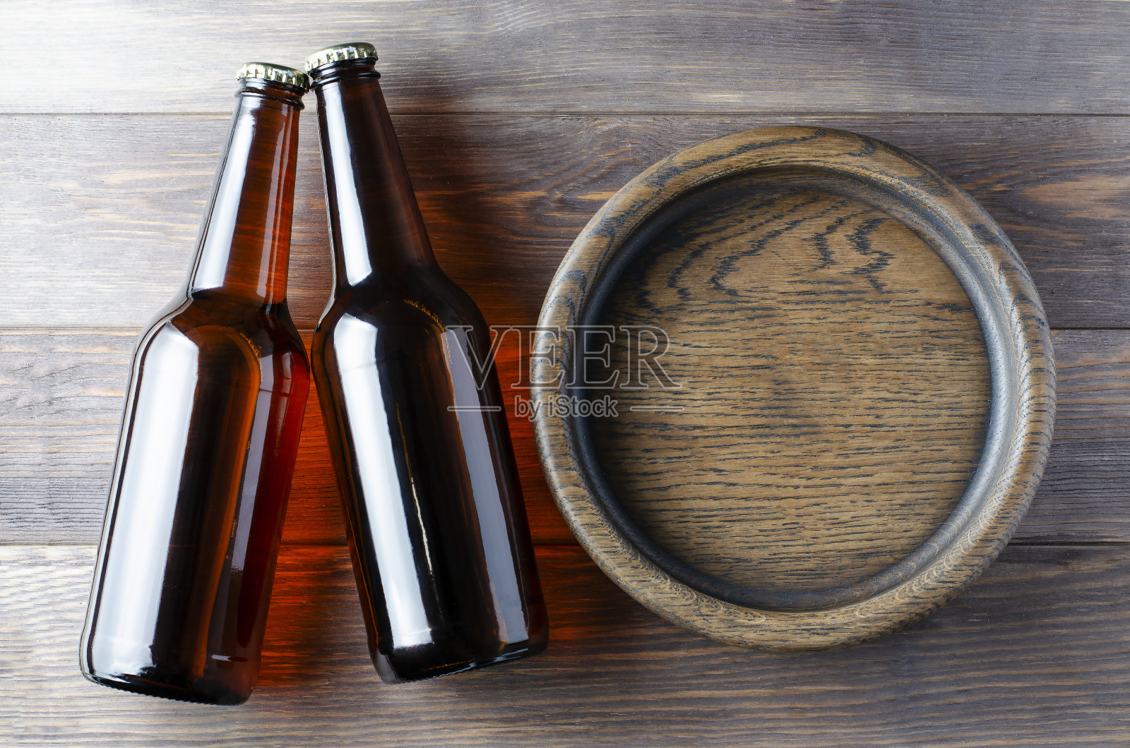 玻璃瓶里的啤酒和装零食的木盘子。布朗木制背景。本空间照片摄影图片