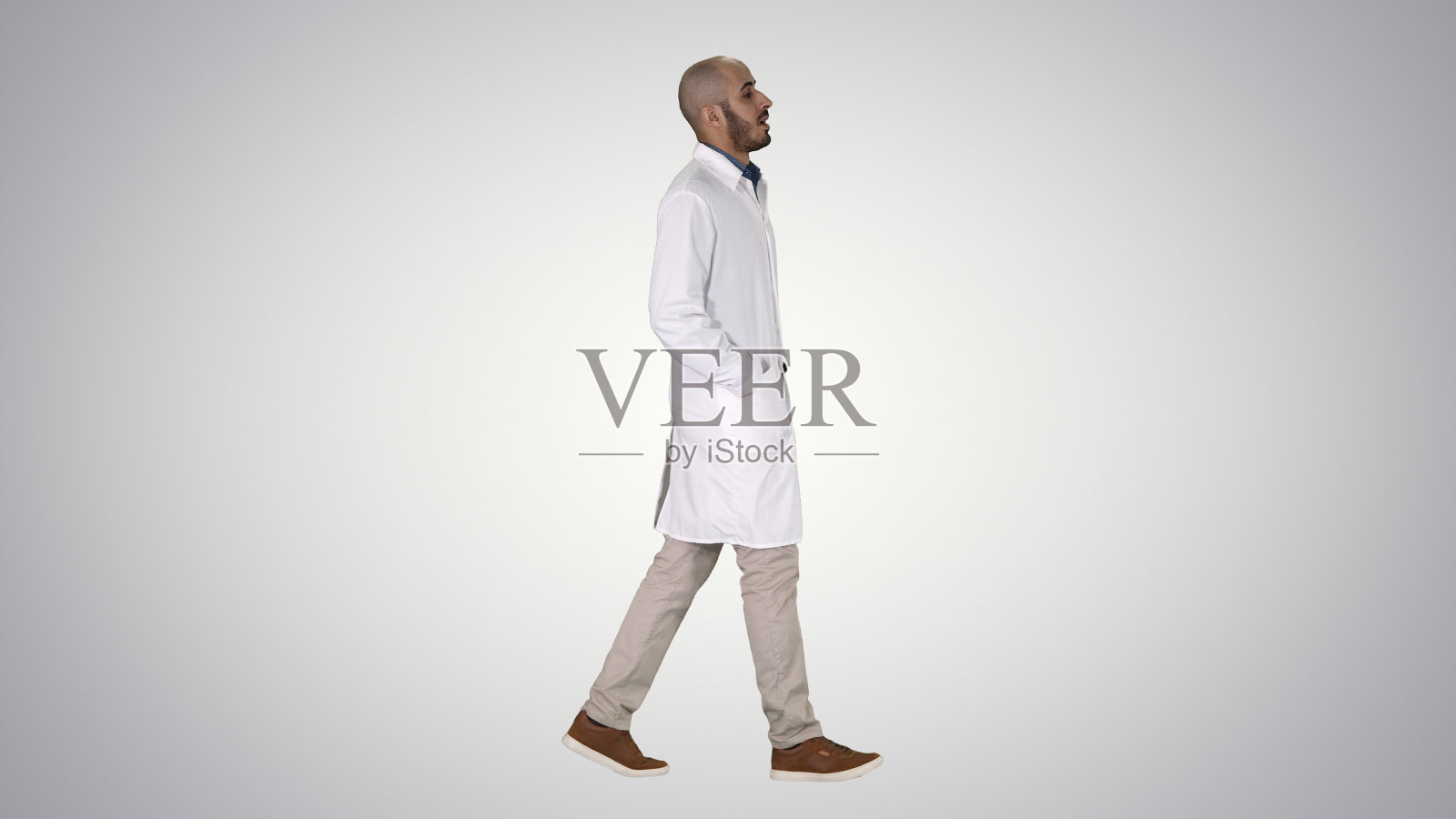 在渐变背景下，医生双手插在口袋里走路照片摄影图片