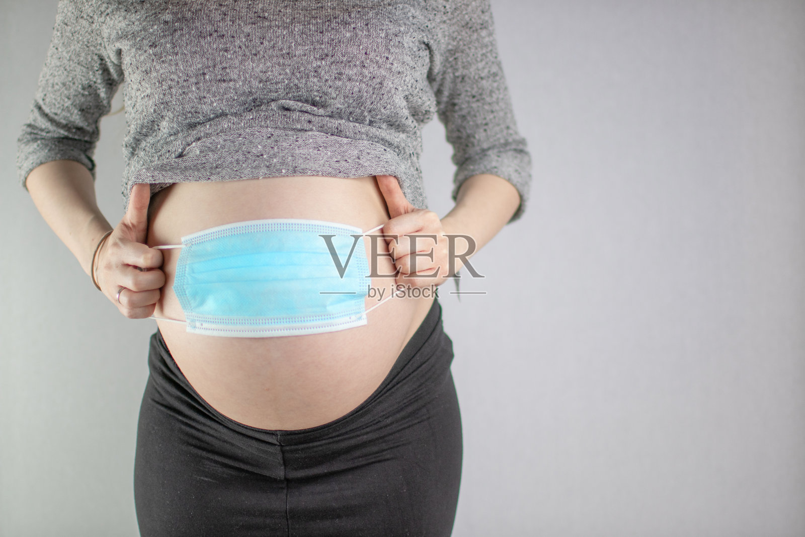 孕妇用口罩遮住肚子。强调了冠状病毒在妊娠期间的危险。空间复制照片摄影图片