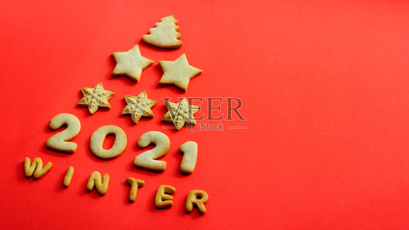 2021年的概念。用红色背景上的饼干做成的圣诞贺卡。圣诞树形状的饼干照片摄影图片