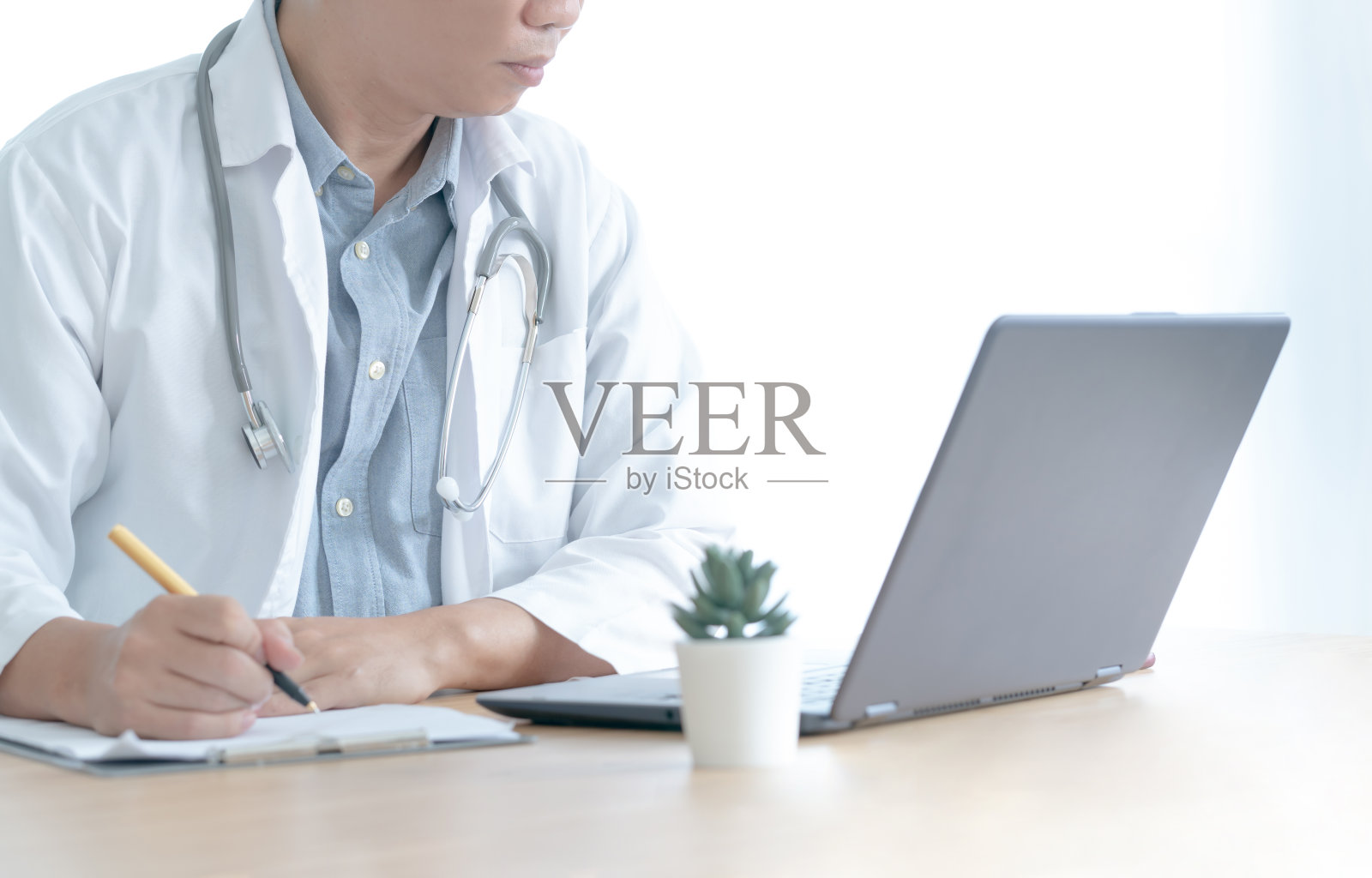 身穿制服的临床医生坐在写字台前用笔记本电脑浏览在线信息照片摄影图片