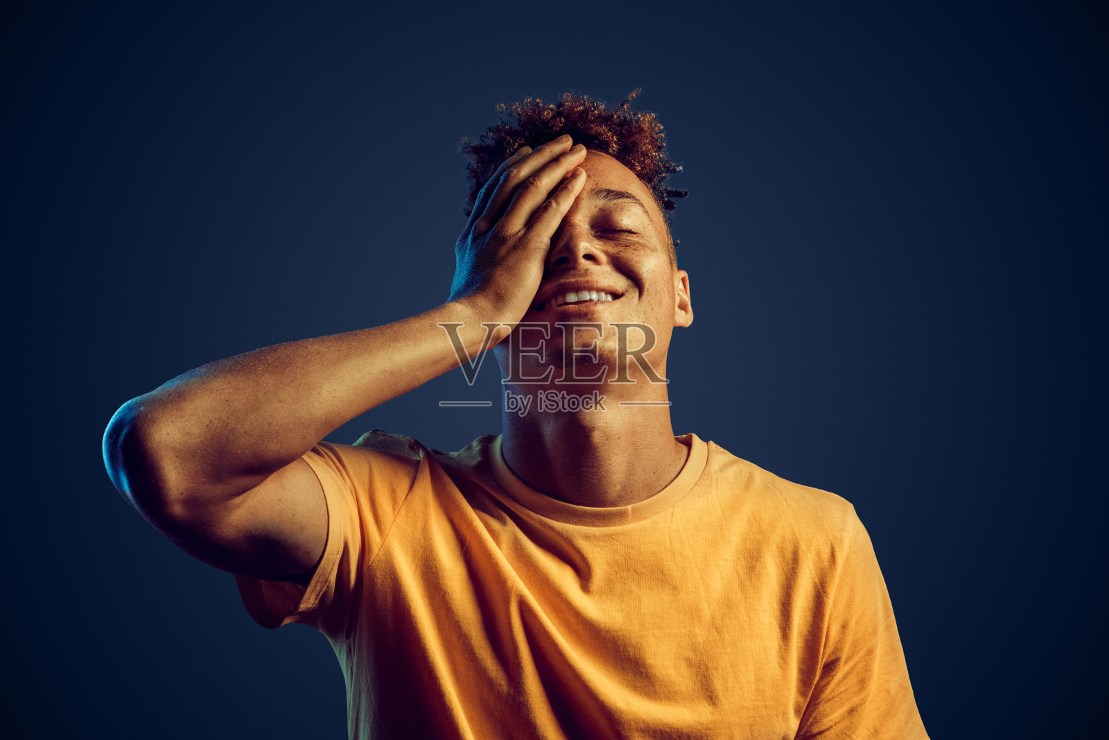 年轻的成年潮人覆盖着脸与手掌和微笑宽照片摄影图片