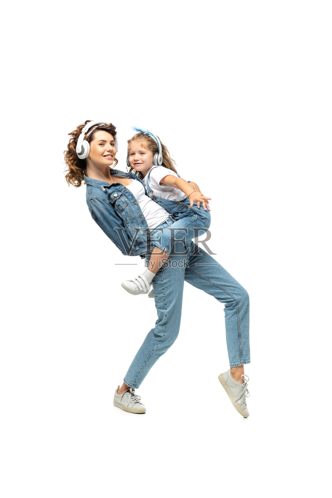 母亲抱着女儿听音乐，戴着耳机孤立在白色照片摄影图片